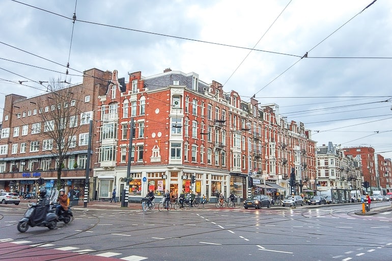 Gebäude aus rotem Backstein an geschäftiger Kreuzung mit Autos in Amsterdam Oud West
