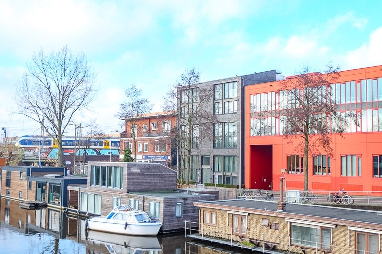 Apartmentgebäude mit Fluss und Hausbooten im Vordergrund in Zeeburg Amsterdam