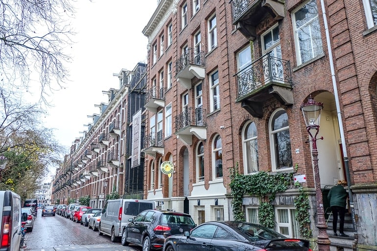 red brick houses in a row with cars parked on street in amsterdam