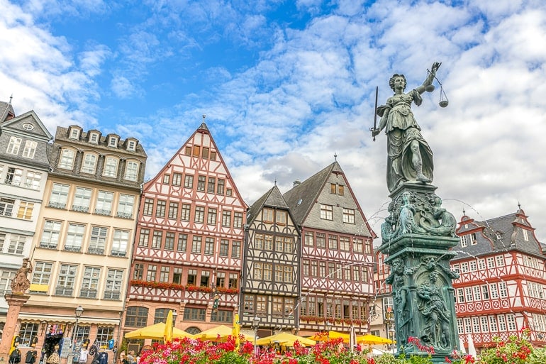 Brunnen mit Bluem und Statue im Vordergrund und Fachwerkhäusern im Hintergrund in Frankfurt