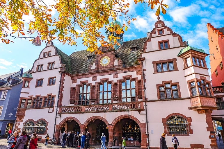 Rosa Gebäude mit braunen Steinen in Altstadt von Freiburg mit bunten Blättern im Bild