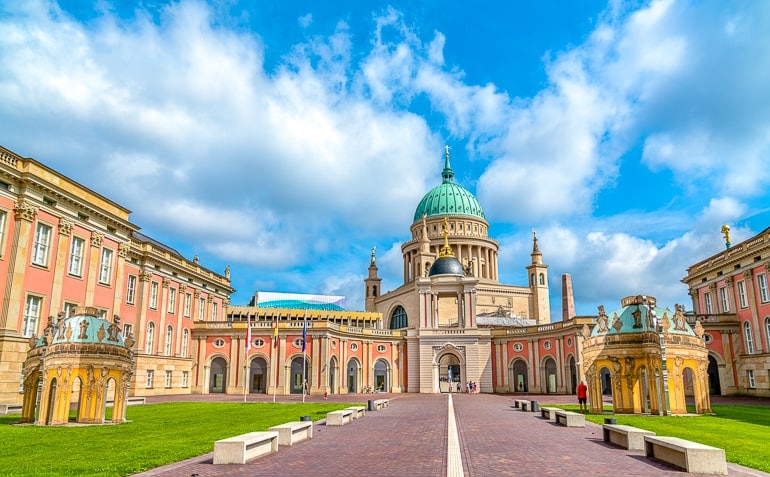 large building with green dome behind and blue sky behind in potsdam germany