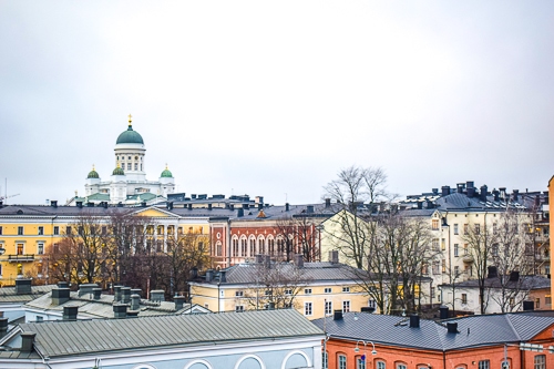 green domes of cathedral with colourful buildings below in helsinki finland