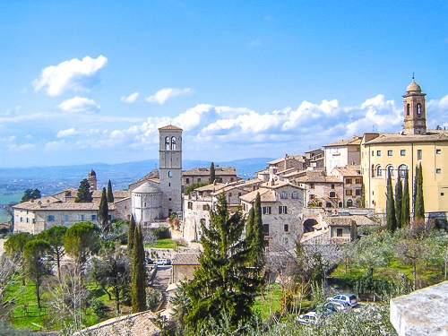 old town buildings on hillside with blue sky behind in italy