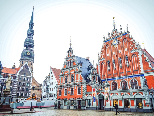 Rathaus aus rotem Stein mit Kirche daneben in Altstadt von Riga