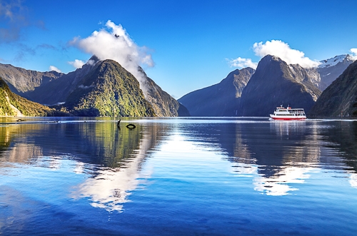 Blaues Wasser mit Boot und Fjorden im Hintergrund in Neuseeland
