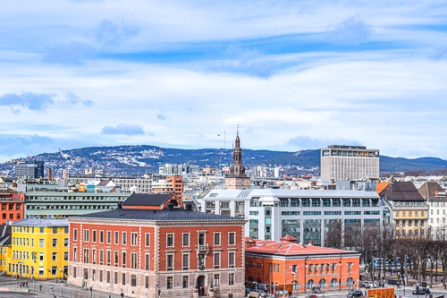 colourful old town buildings with spire and blue sky behind in oslo norway
