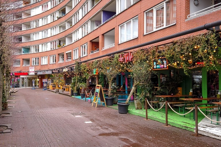 red brick building with restaurant patios on the ground level in amsterdam.