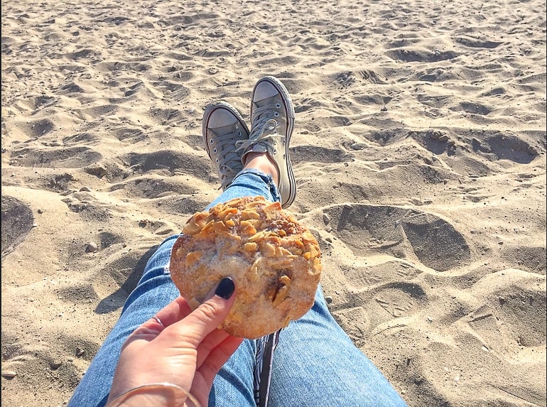 woman sitting on beach showing legs holding cookie