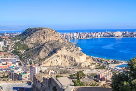 view of rocky cliff with blue water and beach beside things to do in alicante spain
