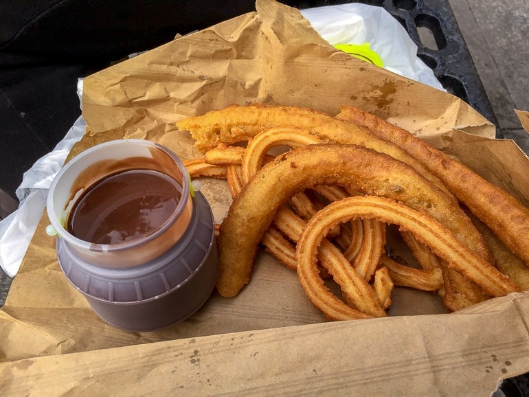 churros in paper dish with sauce on lap in alicante