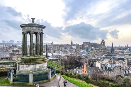 large monument with city and castle behind in edinburgh travel guide