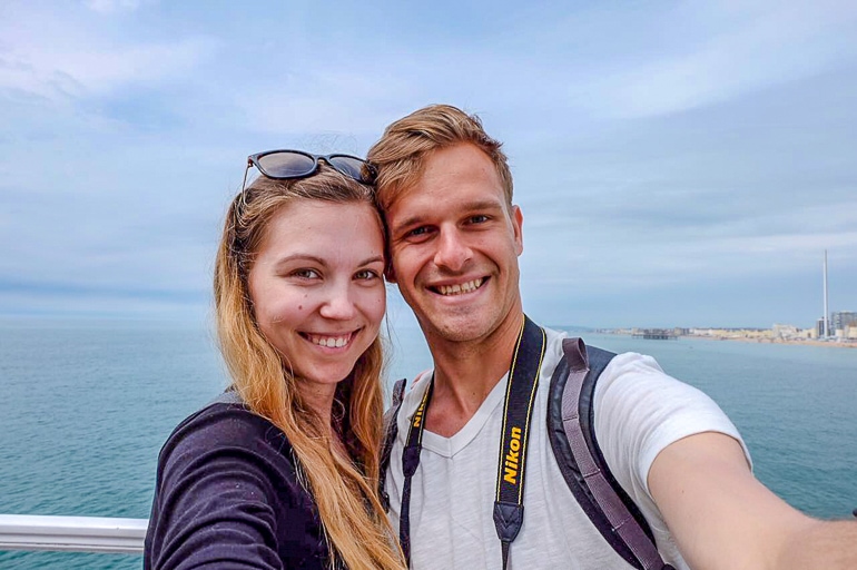 Frau und Mann posieren für Foto mit blauem Meer und Himmel im Hintergrund.