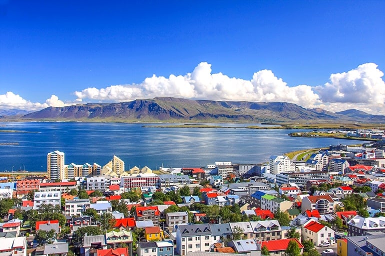 Bunte Dächer von Häusern in Reykjavik mit Wasser und Bergen im Hintergrund