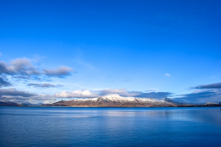 blue water in front of snowy mountain esja with blue sky in reykjavik