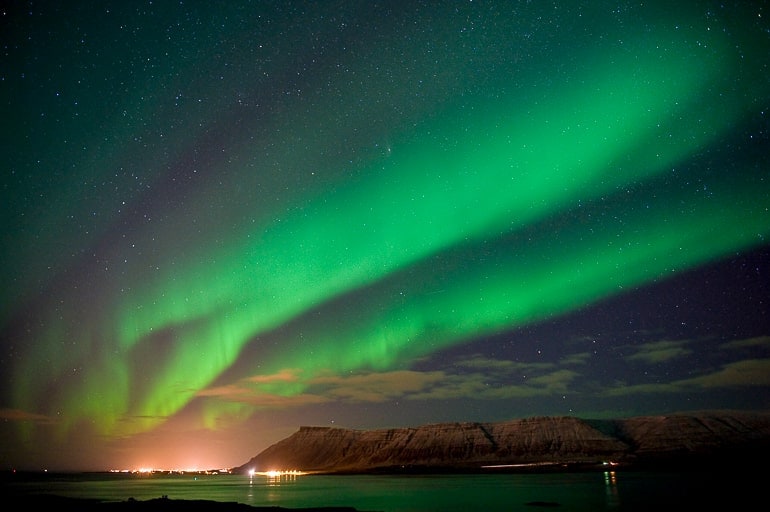Grüne Nordlichter über dunkler Landschaft auf Island