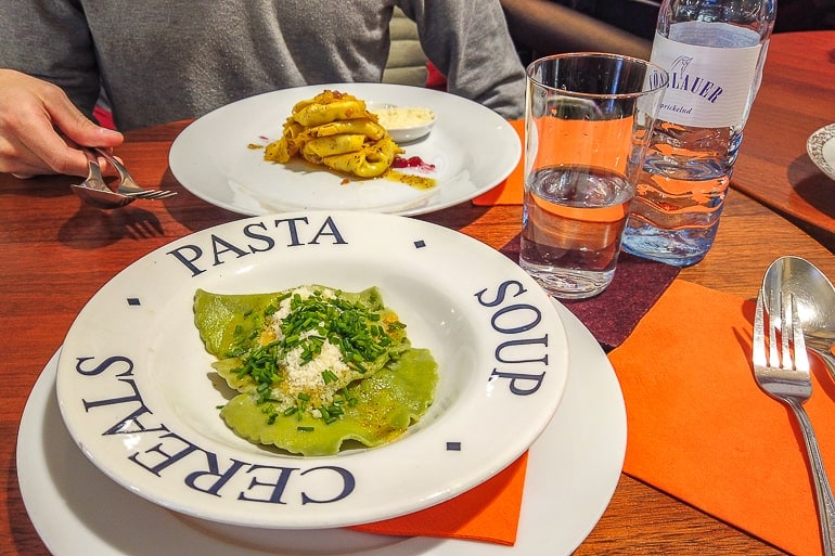two white plates of pasta on orange table in food hall innsbruck