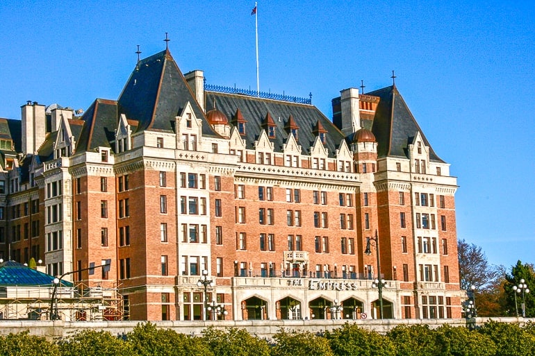 large brick hotel building with flags on top fairmont empress victoria bc