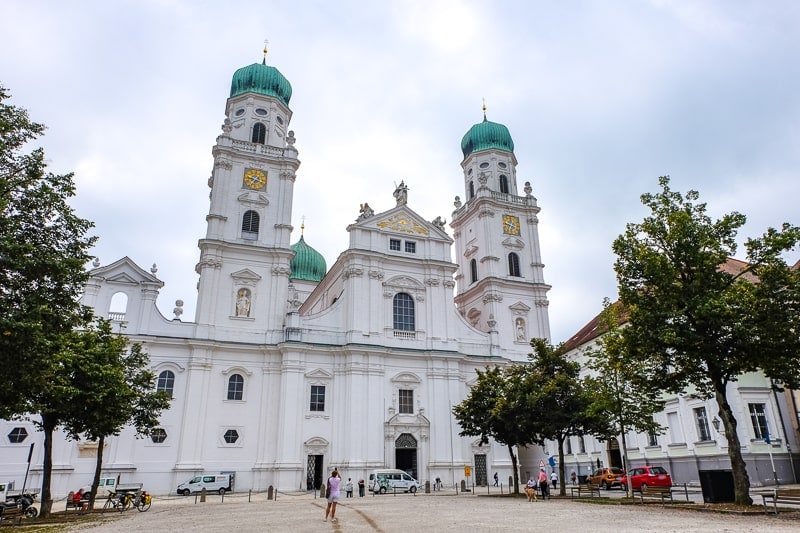old white cathedral with green domes and square in front in passau old town