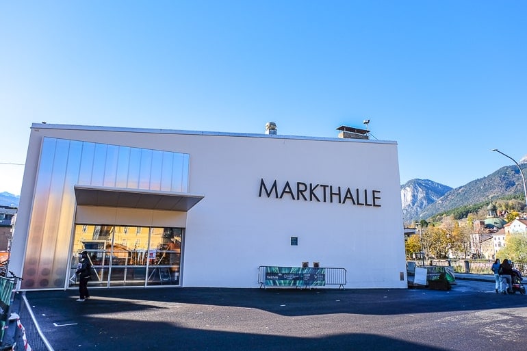 large white market hall building with parking lot in front in innsbruck