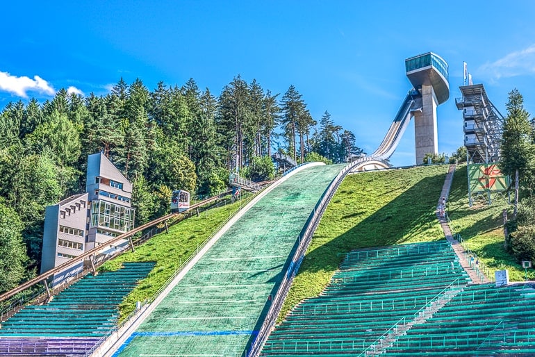 Große Skischanze mit Sitzen in Stadion und grünen Bäumen herum