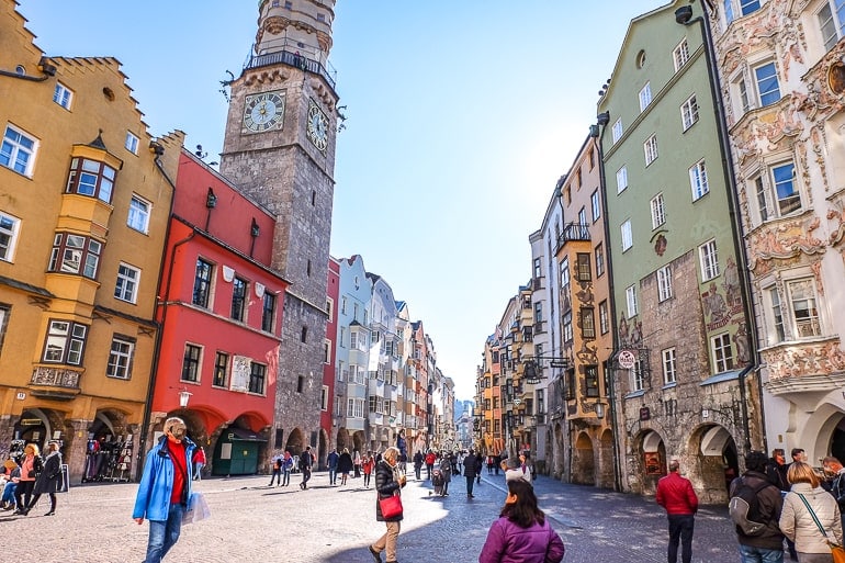 colourful old town buildings with clock tower and people shopping one day in innsbruck