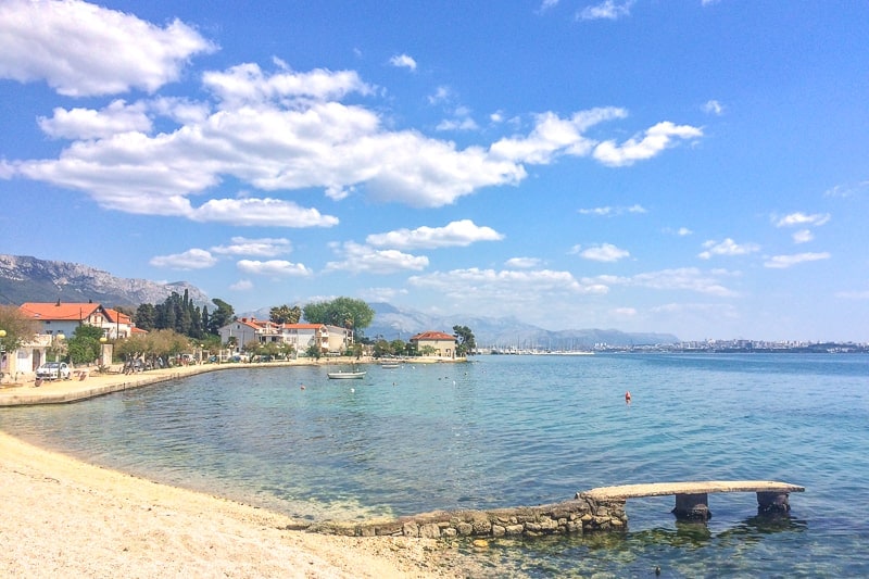 Blauer Himmel mit kroatischer Küste und Strand im Vordergrund