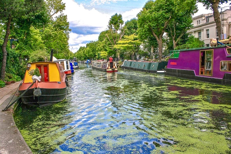 bunte Boote auf kleinem Kanal mit grünem Schaum auf der Oberfläche in London England