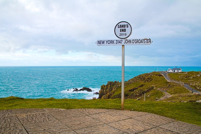 white sign for lands end with ocean behind in cornwall