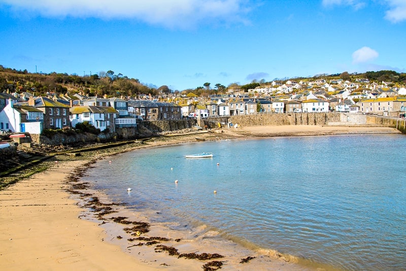 small seaside village of mousehole with sandy beach and shallow water