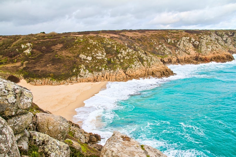 blaue Küstenlinie mit Felsklippen dahinter in Porthcurno Cornwall