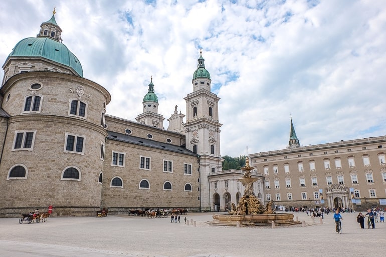 large open square with fountain in middle and cathedral behind in salzburg