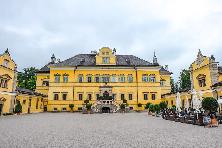 Gelbes Schlossgebäude mit Innenhof und Tischen