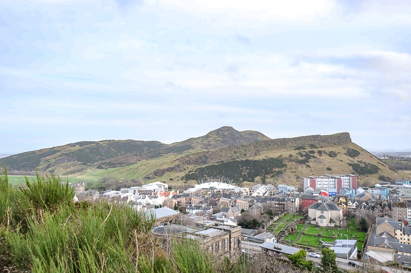 Ein großer felsiger Hügel aus der Ferne mit Stadtgebäuden darunter.