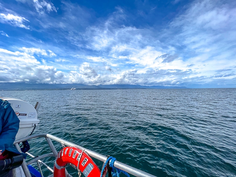Offener Ozean vom Boot aus mit blauem Himmel und Wolken darüber.