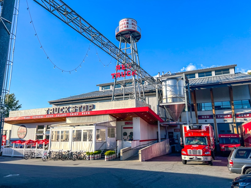 large brewery building with water tower and red trucks in front.