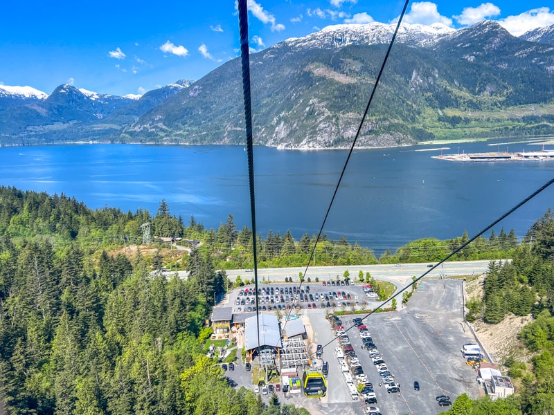 view from rising gondola with blue water and mountains in distance.
