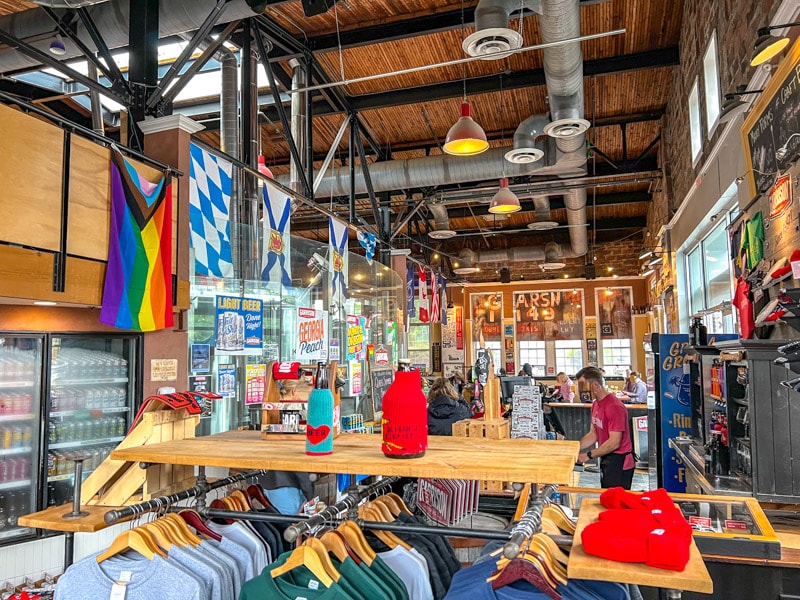 colourful interior of lively brewery with people sitting and merchandise hanging in front.