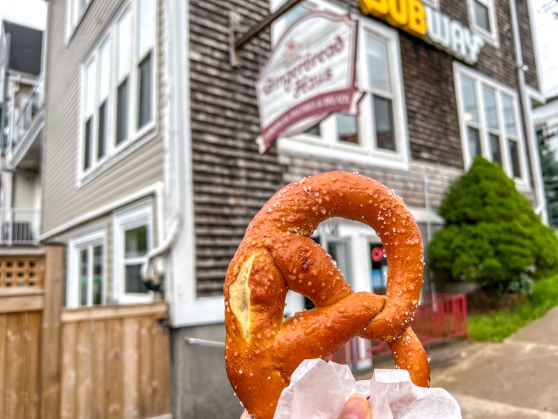 baked pretzel hand in hand with bakery building in background.