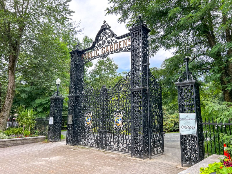 large black iron gates with green trees behind in public gardens.