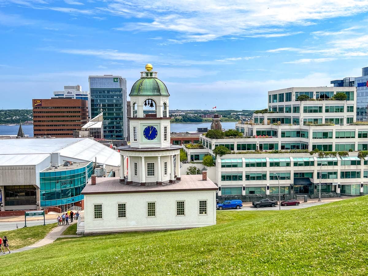 clock tower with blue clock in foreground with city buildings in Halifax behind.