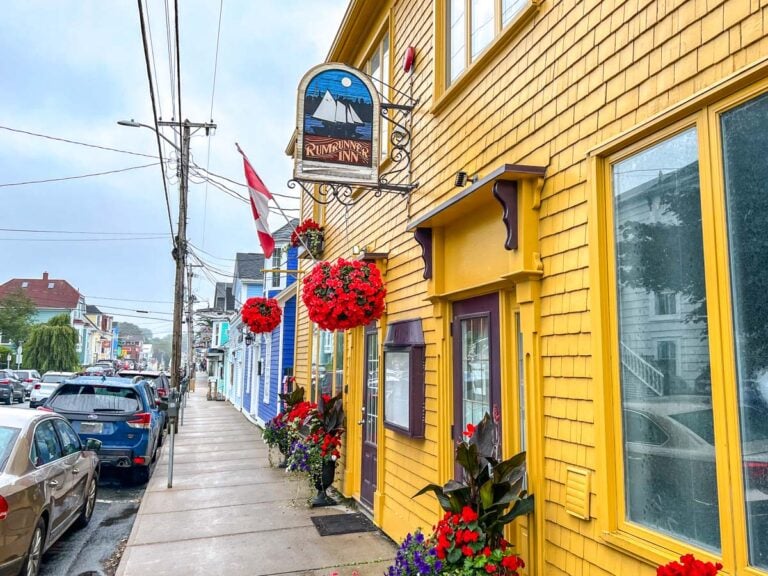 colourful yellow wooden inn building with sidewalk beside and cars parked on street in lunenburg.