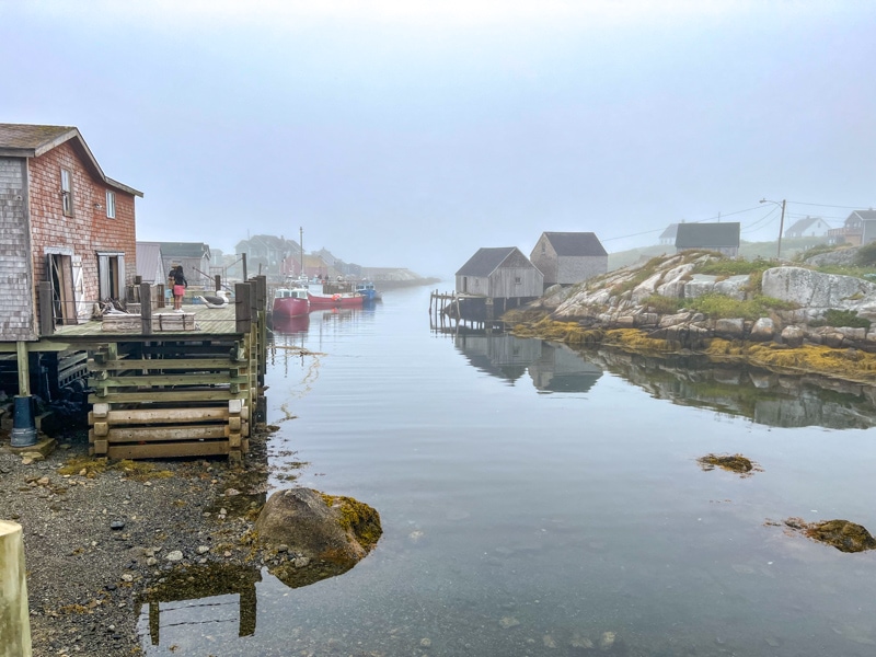 Fischerbucht mit kleinen Gebäuden am Ufer bei Nebel.