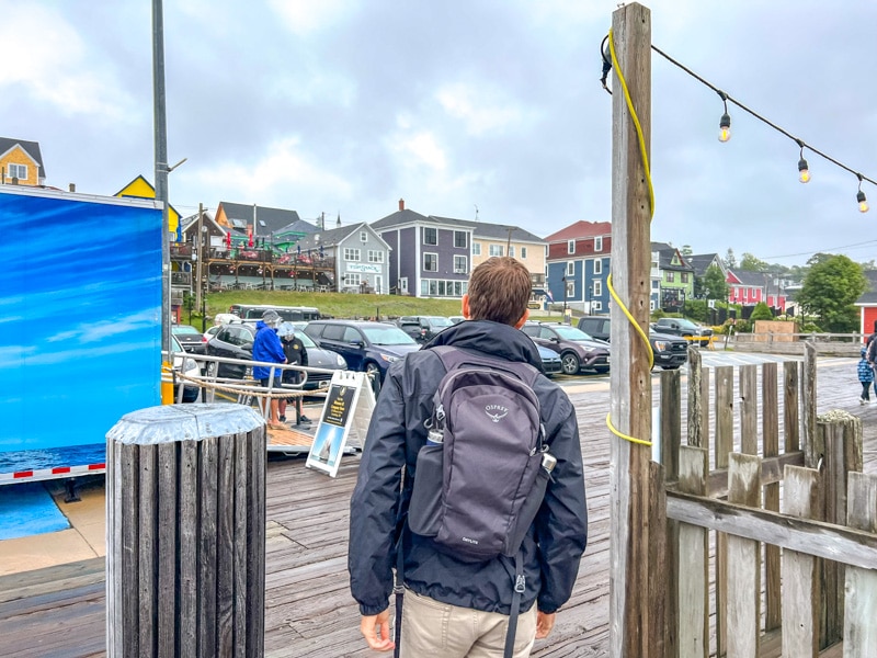 Mann mit Rucksack beim Spaziergang am Hafen mit den bunten Häusern im Hintergrund.