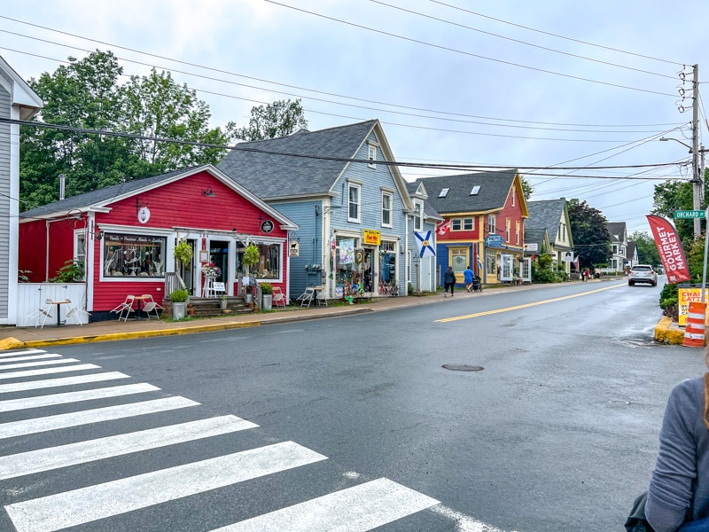 colourful shop fronts with paved street in front and grey sky above.