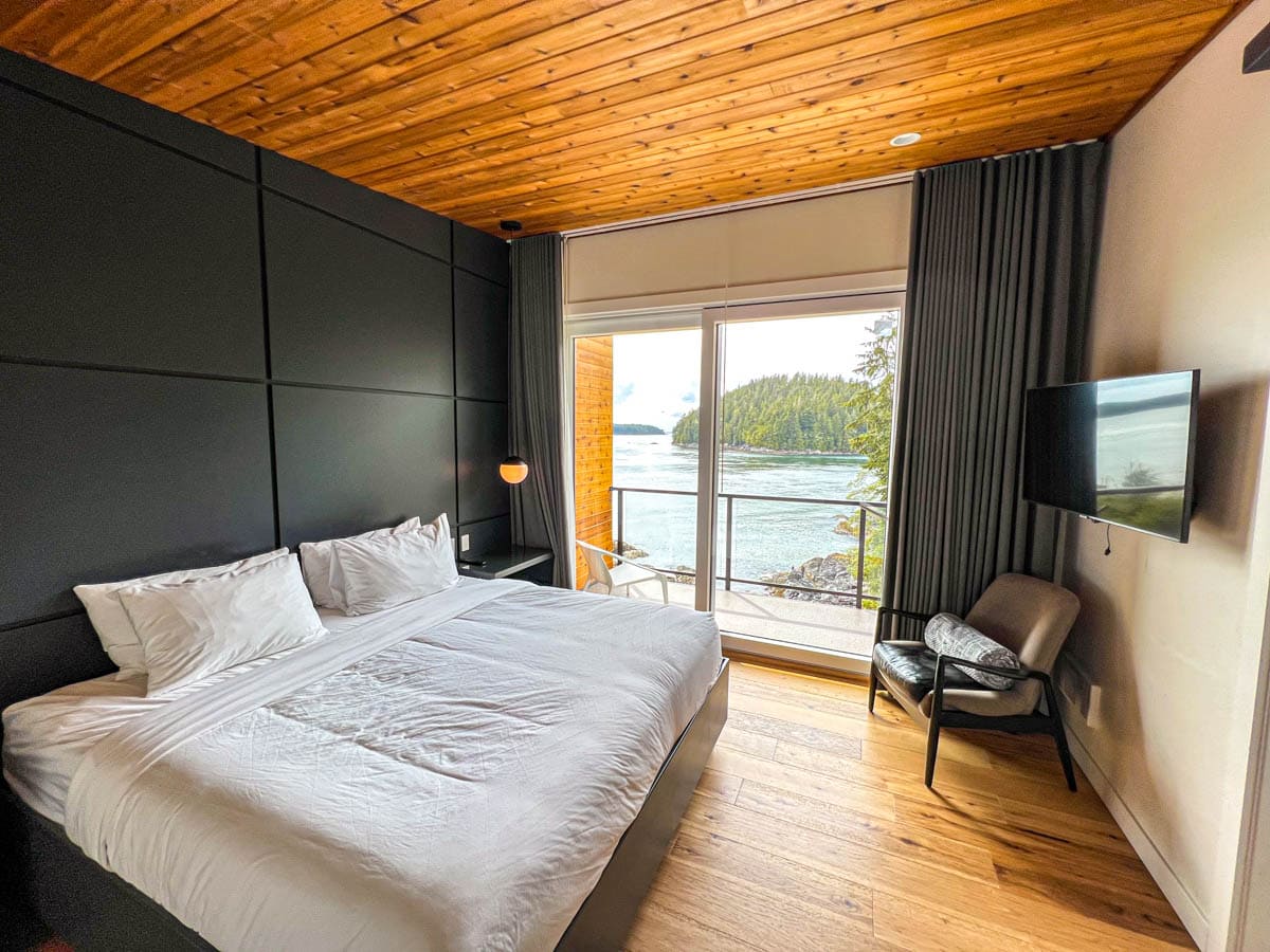 boutique hotel room at duffin cove resort with large king bed with white sheets and balcony view beyond glass door.