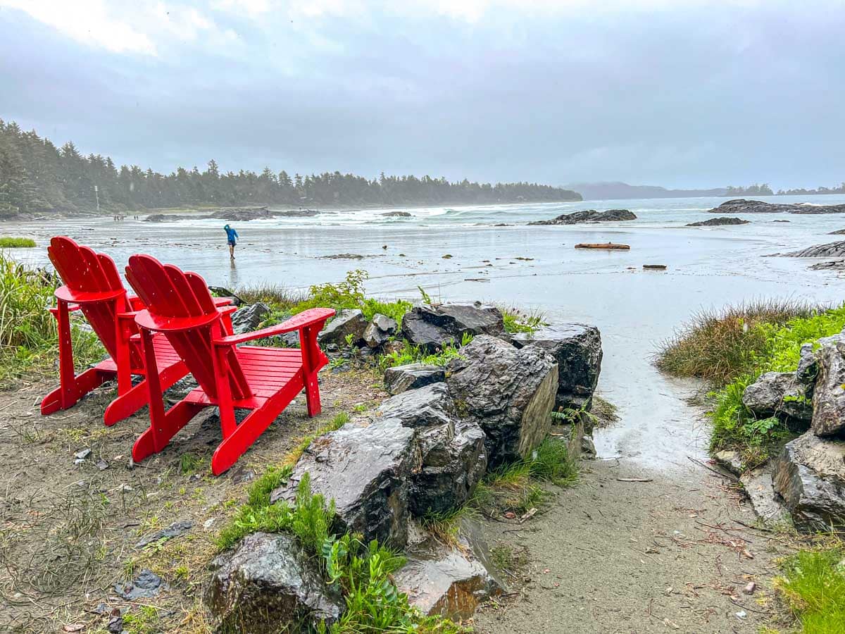 red chairs in the rain overlooking ocean waves with grey clouds overhead in tofino.
