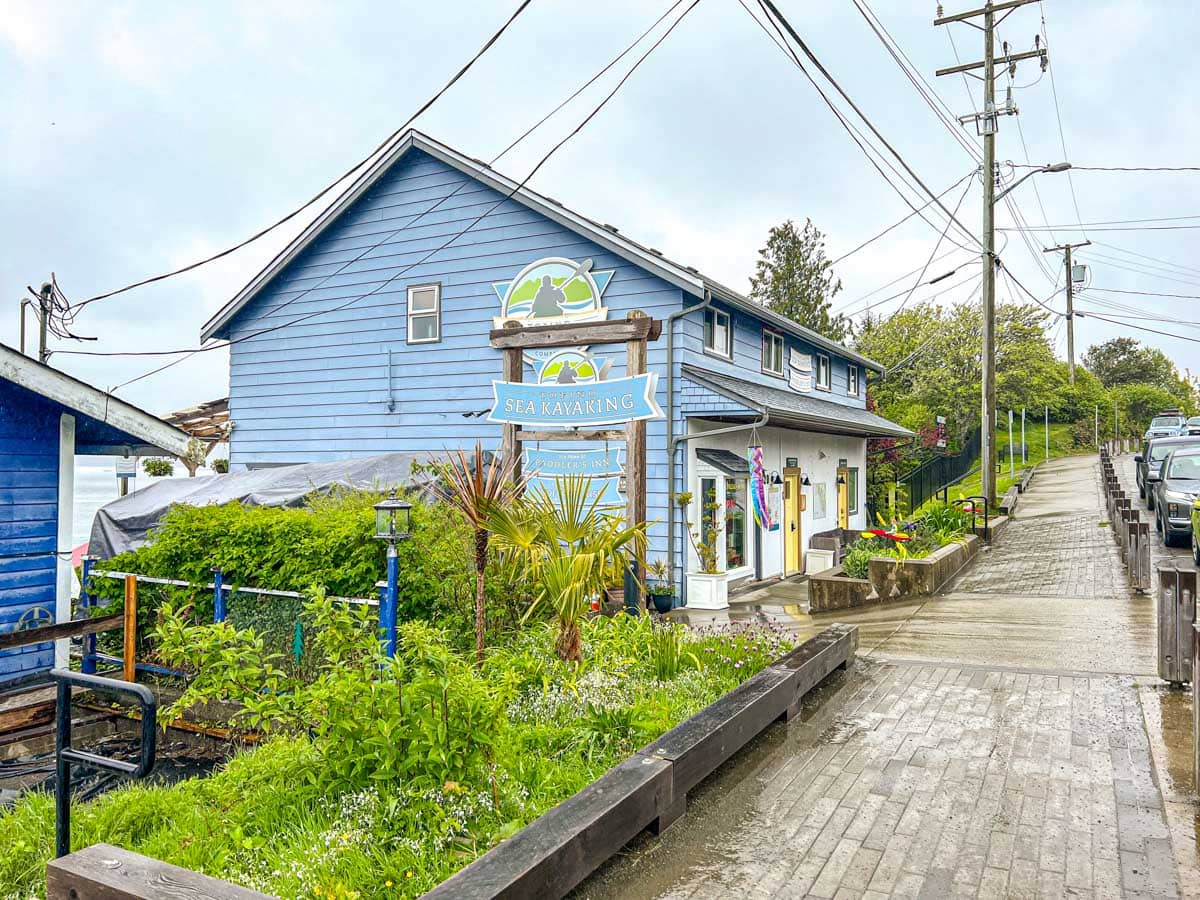 blue inn house in tofino with wet sidewalk and cars parked in front.