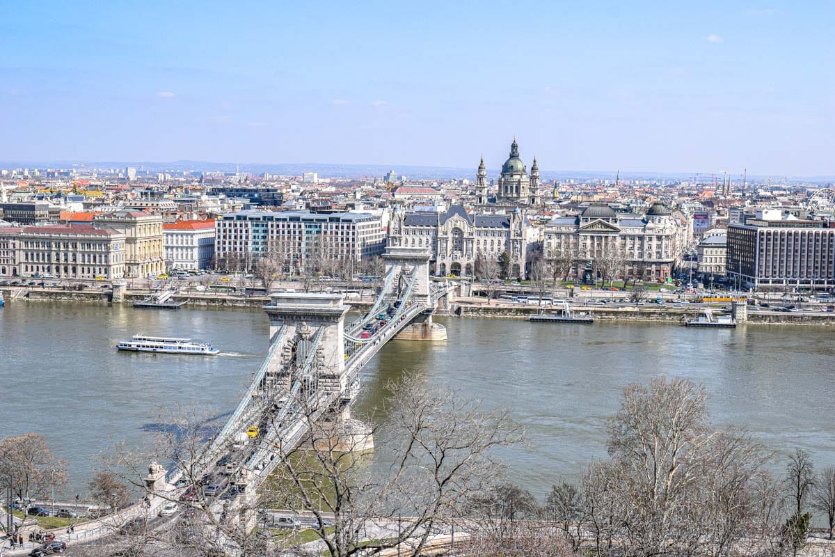 wide shot of buildings in city centre budapest with danube river and bridge in front.
