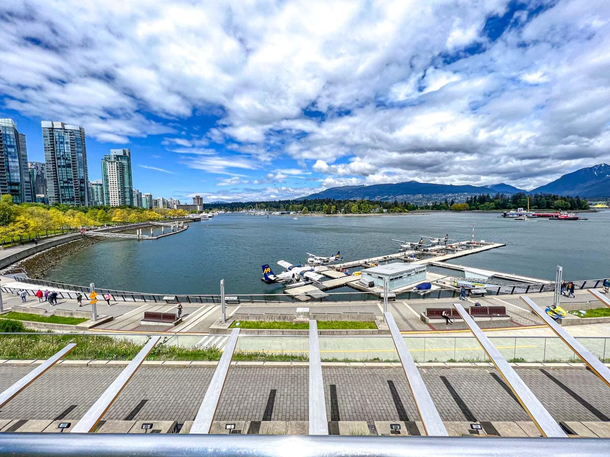 wide angle view of harbour airport with large downtown buildings and mountains in distance.